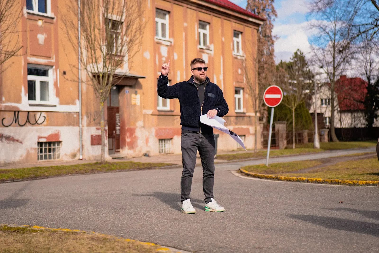 Maxim Ponomarenko vor einem Backstein-Mietshaus, in der Hand Unterlagen zur Immobilie